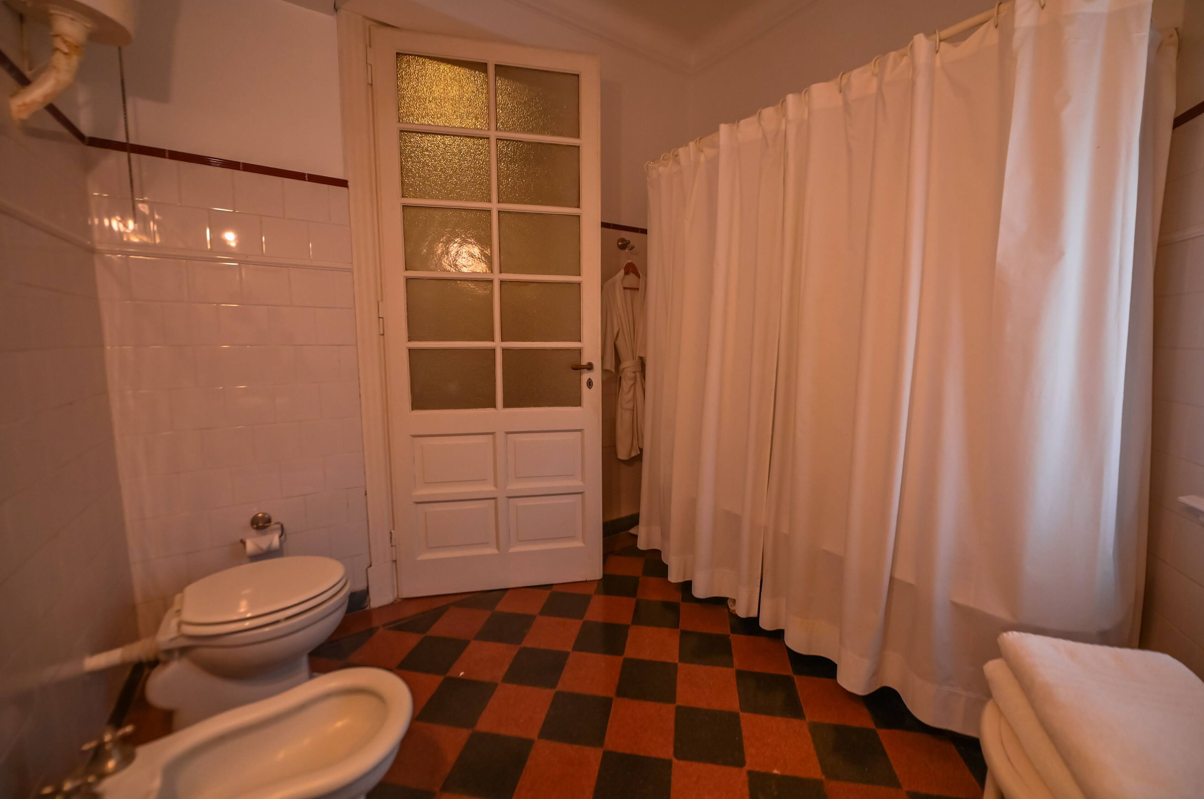 Une salle de bain équipée de toilettes, d’un bidet et d’un rideau de douche.