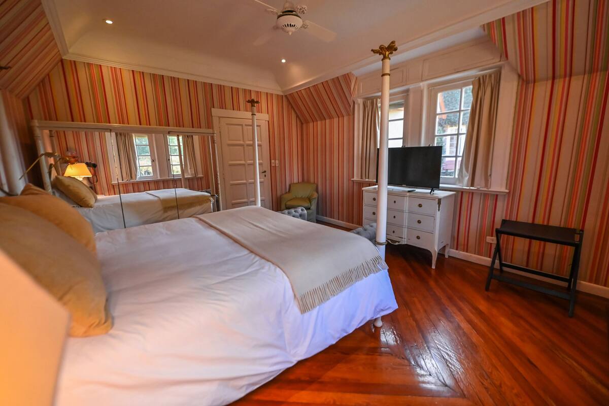 Quarto com cama grande, televisão, escrivaninha e cadeira.