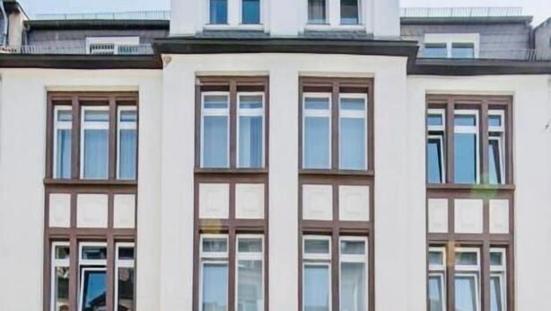 A two-story building with a symmetrical facade, featuring a central entrance with a dark-colored door, flanked by two windows on each side. - Aparthotel TU-TU (Essen)