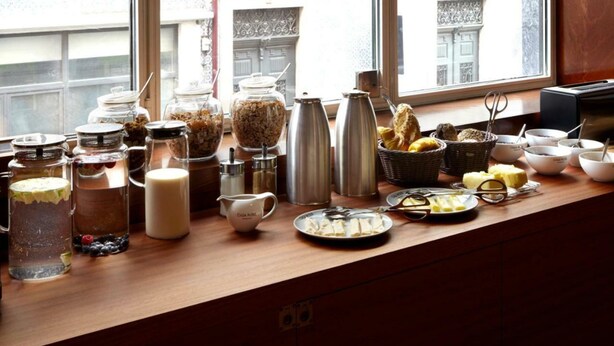 Buffet de l'esmorzar amb diversos plats i condiments sobre un taulell de fusta al costat d'una finestra.