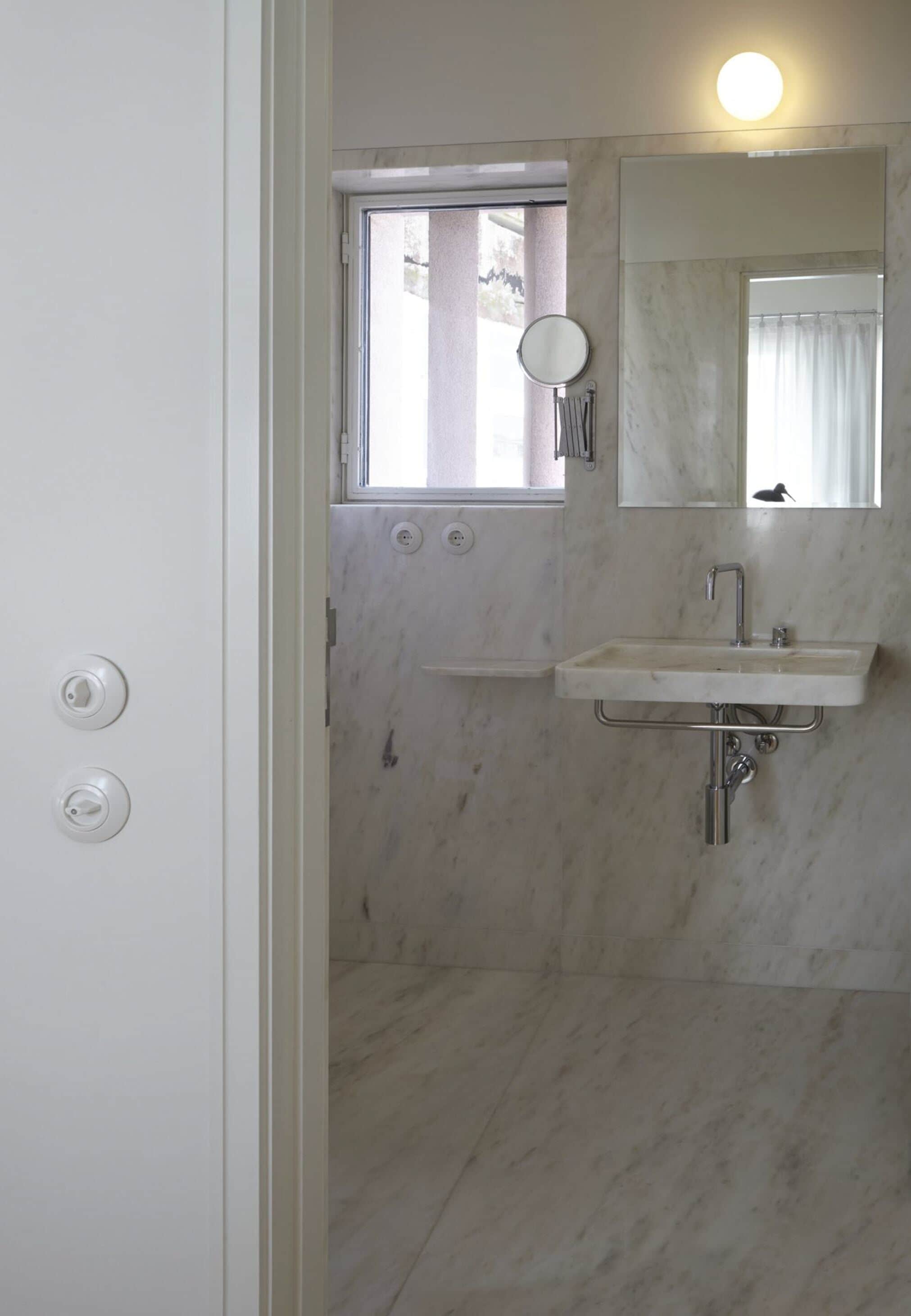 A bathroom with a marble sink, a mirror, and a window.