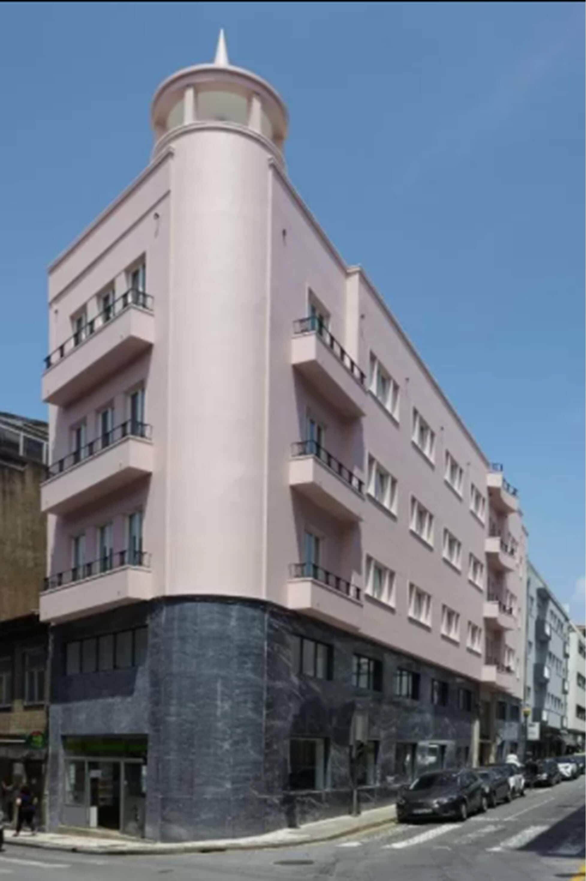 Un immeuble à plusieurs étages, doté d’une façade rose et d’une section cylindrique.