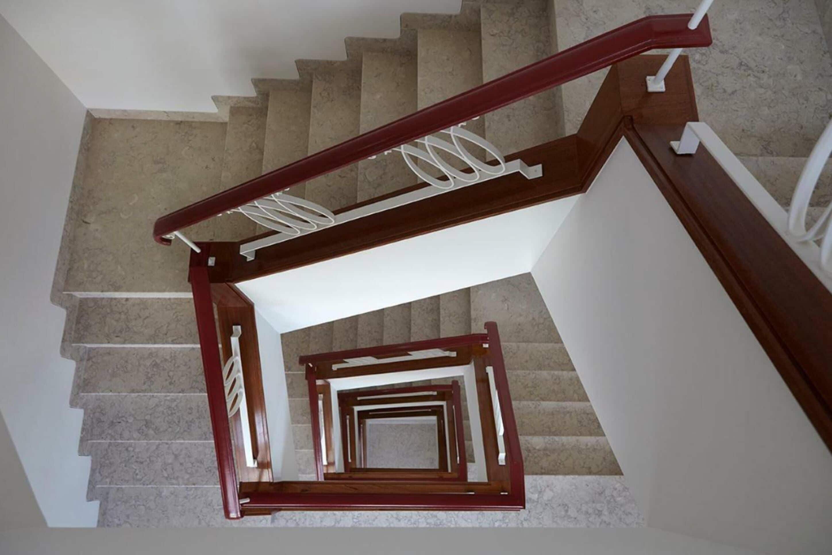 Eine Wendeltreppe mit hölzernem Geländer und weißen Spindeln.