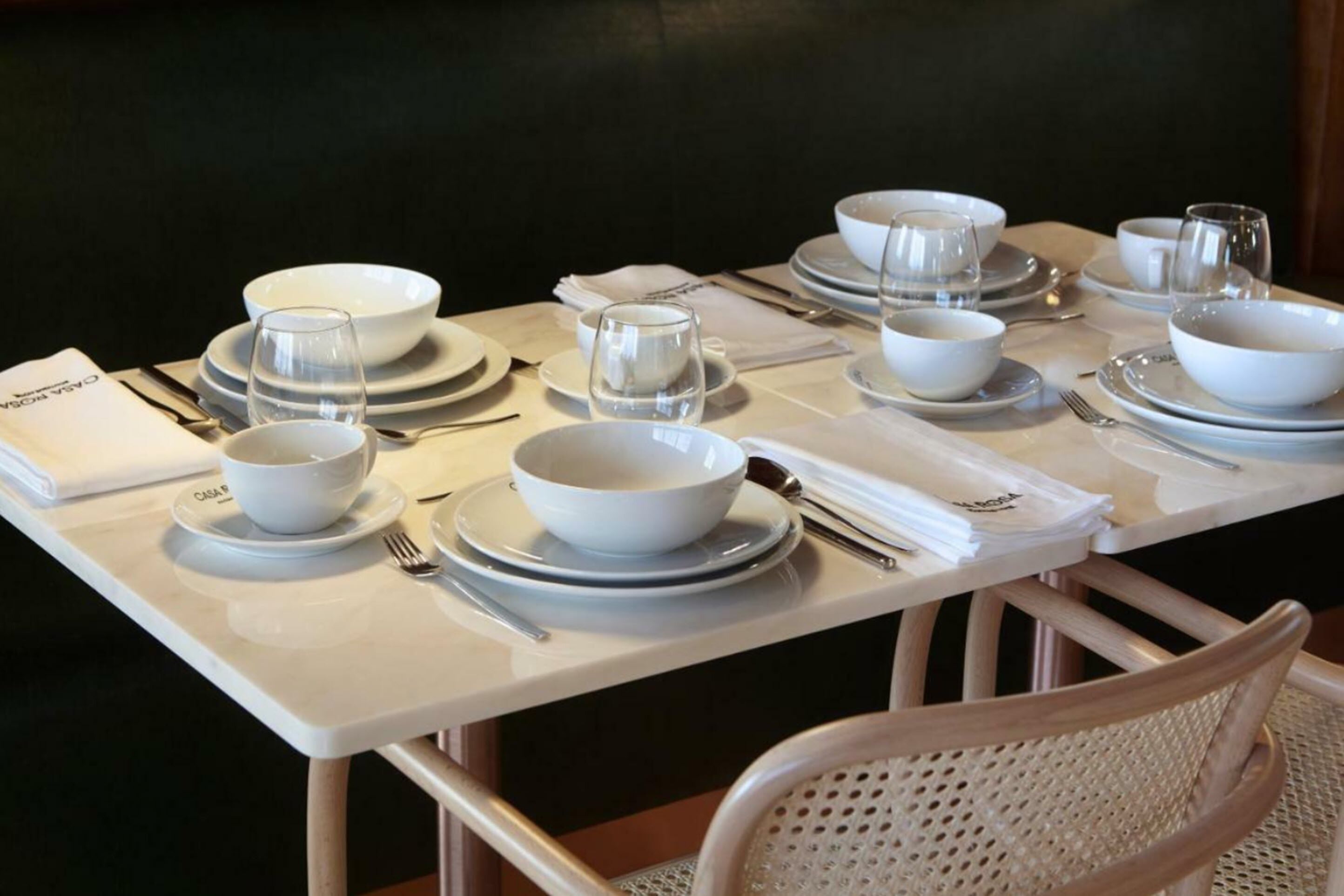 Une table à manger élégamment dressée, avec de l’argenterie blanche, des assiettes, des bols et des verres, ainsi que des serviettes pliées et des couverts.