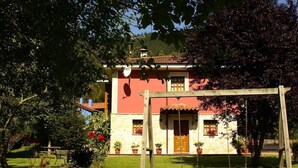 A traditional building with a stone facade, a wooden swing set, and a well-maintained garden. - Casa Marian (Parres)