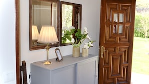 A wooden door with a geometric pattern, a light blue cabinet with a lamp and framed picture, and a chair. - Casa Marian (Parres)