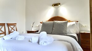A neatly made bed with white linens and towels, a wooden headboard, and a bedside table with a lamp. - Casa Marian (Parres)