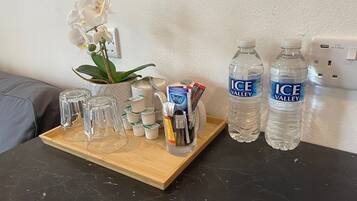 Ein Tablett mit einer weißen Orchidee, einer Glasgießkanne und zwei Flaschen Ice Valley Wasser auf einer dunklen Arbeitsplatte.