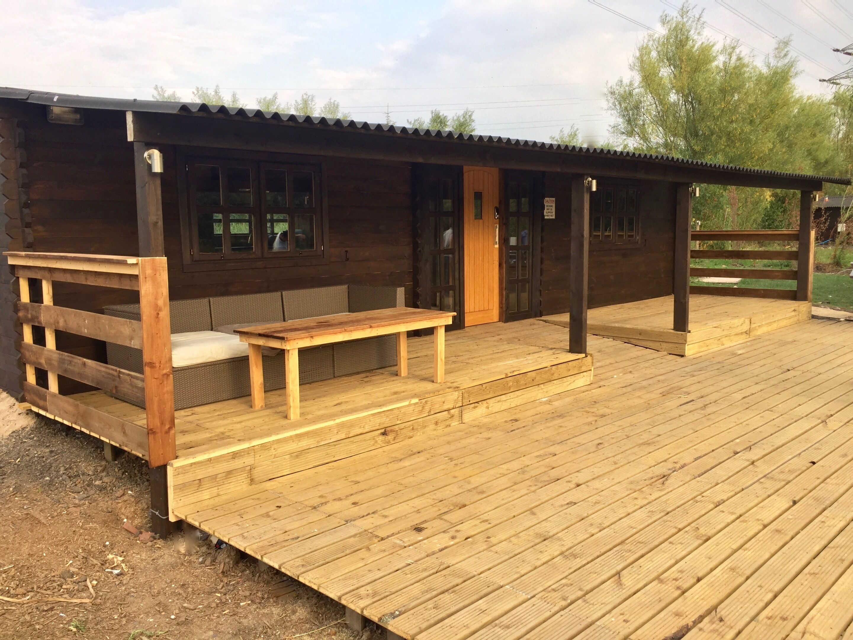 A wooden cabin with a porch, a bench, and a small table.
