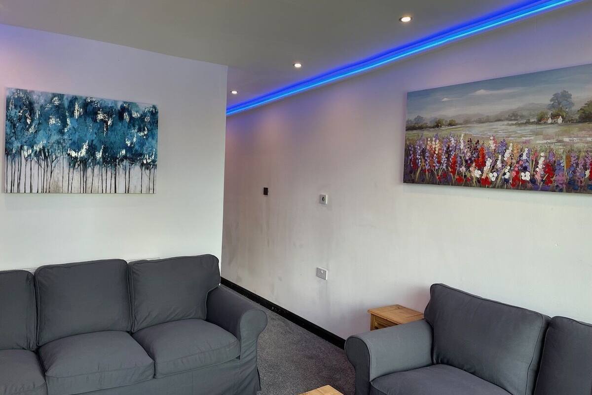 A modern living room with grey sofas, a small wooden table, and two wall-mounted paintings.