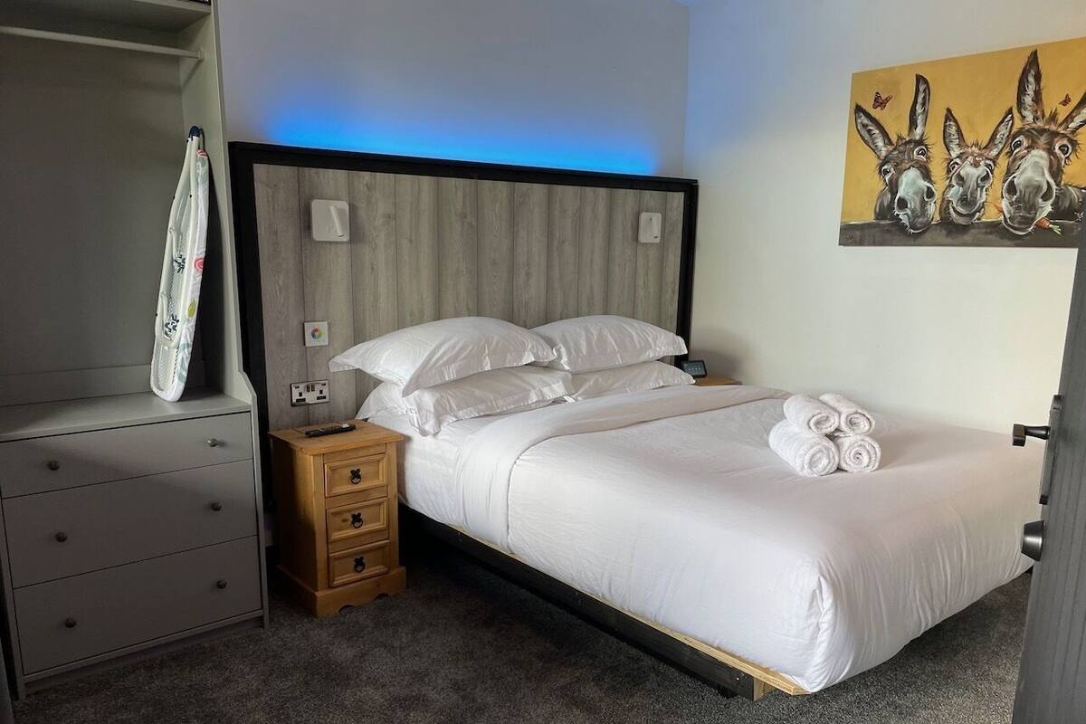 A bedroom with a bed, a nightstand, a dresser, and a painting on the wall.