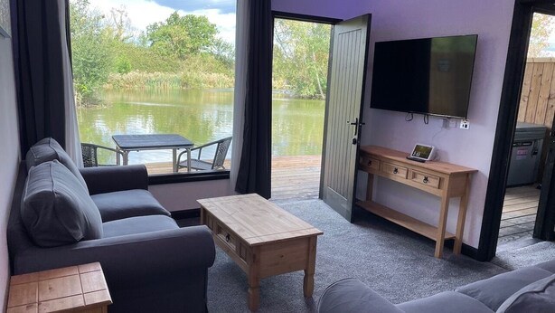 Una habitación con sofá, una mesa de centro, televisión y vistas a un lago.