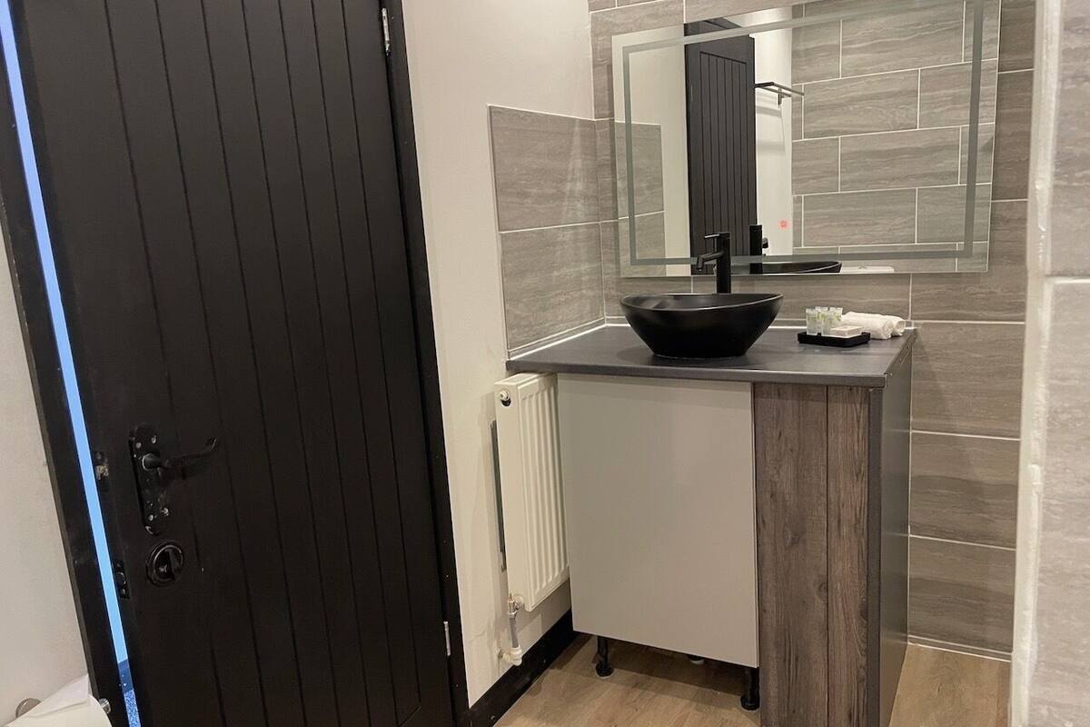 A modern bathroom with a black sink, white cabinets, and a mirror above the sink.