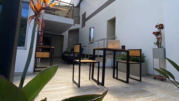 A modern interior with a glass ceiling, a dining area with tables and chairs, and potted plants. - Hotel Campo Real (Marinilla)