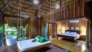 Una habitación de madera con una cama, una bañera y un ventanal grande.