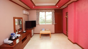 A hotel room with a television, a small table, a mirror, and a window with curtains. - Jumunjin Hotel (Gangneung)