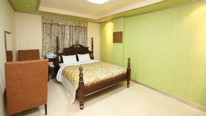 A hotel room with a bed, a chair, a nightstand, and a mirror. - Jumunjin Hotel (Gangneung)