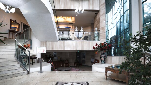 A spacious lobby with a grand staircase, a large decorative floor pattern, and a modern chandelier. - Jumunjin Hotel (Gangneung)