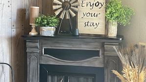Ein Kamin mit einem Schild, auf dem steht 'Enjoy your stay', eine Windmühle und ein Fernseher, der darüber angebracht ist.