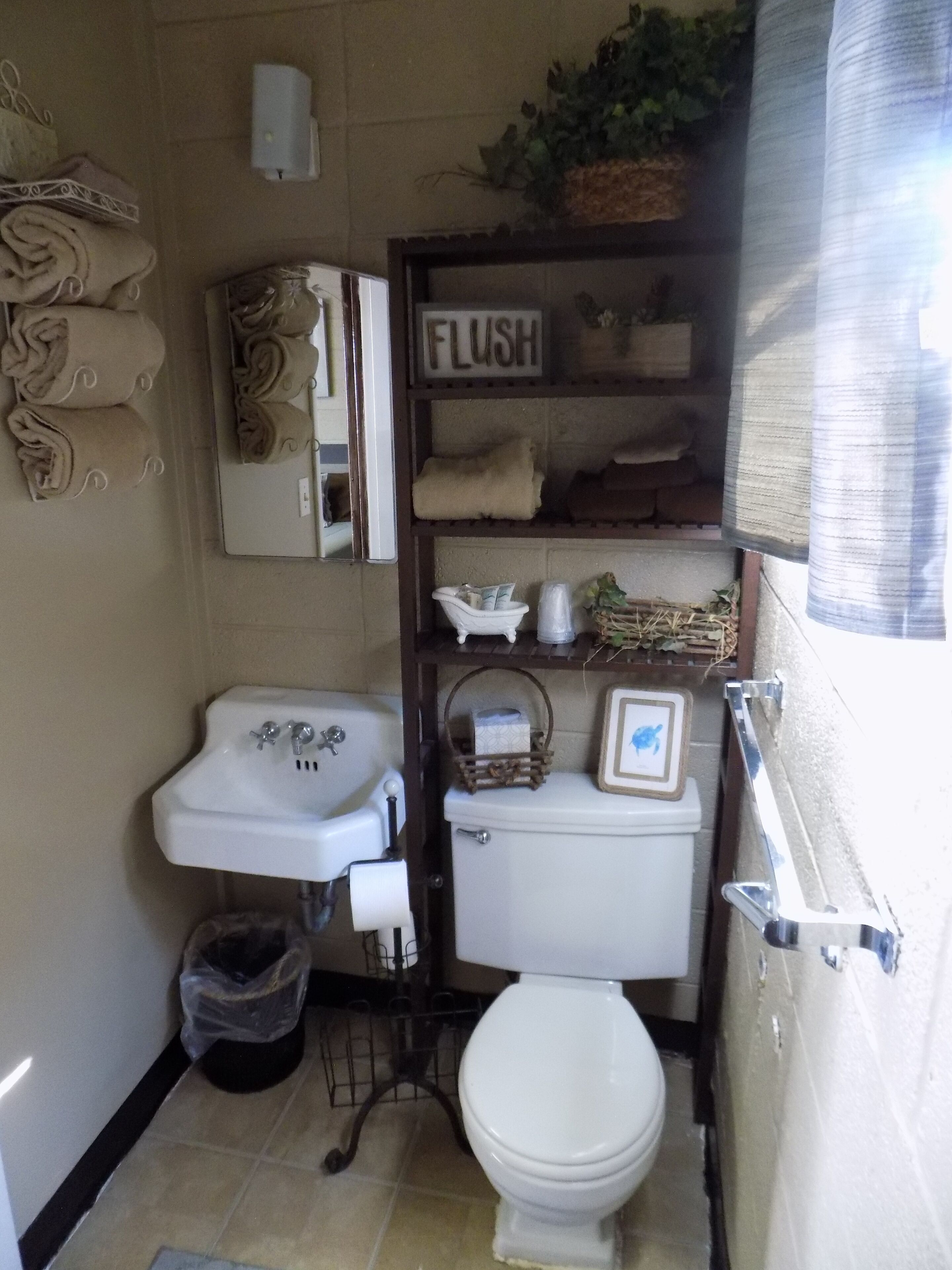 Un baño pequeño con lavamanos, inodoro y un estante con toallas.