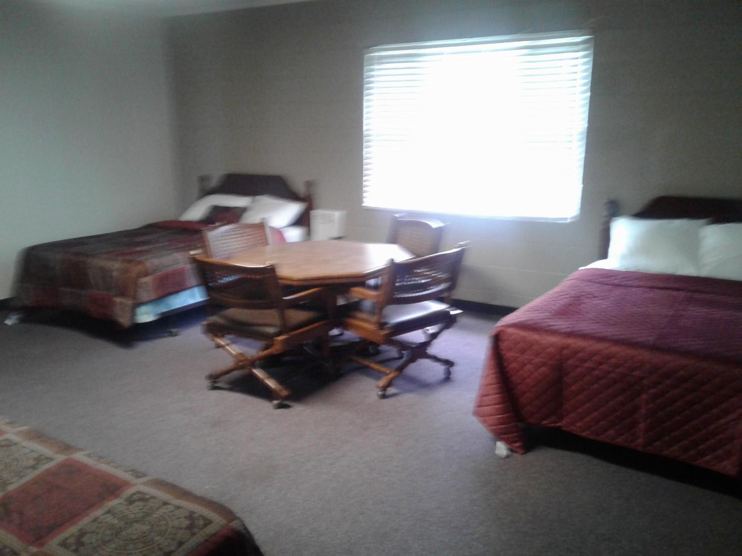 A bedroom with a bed, a desk with a chair, and a window.