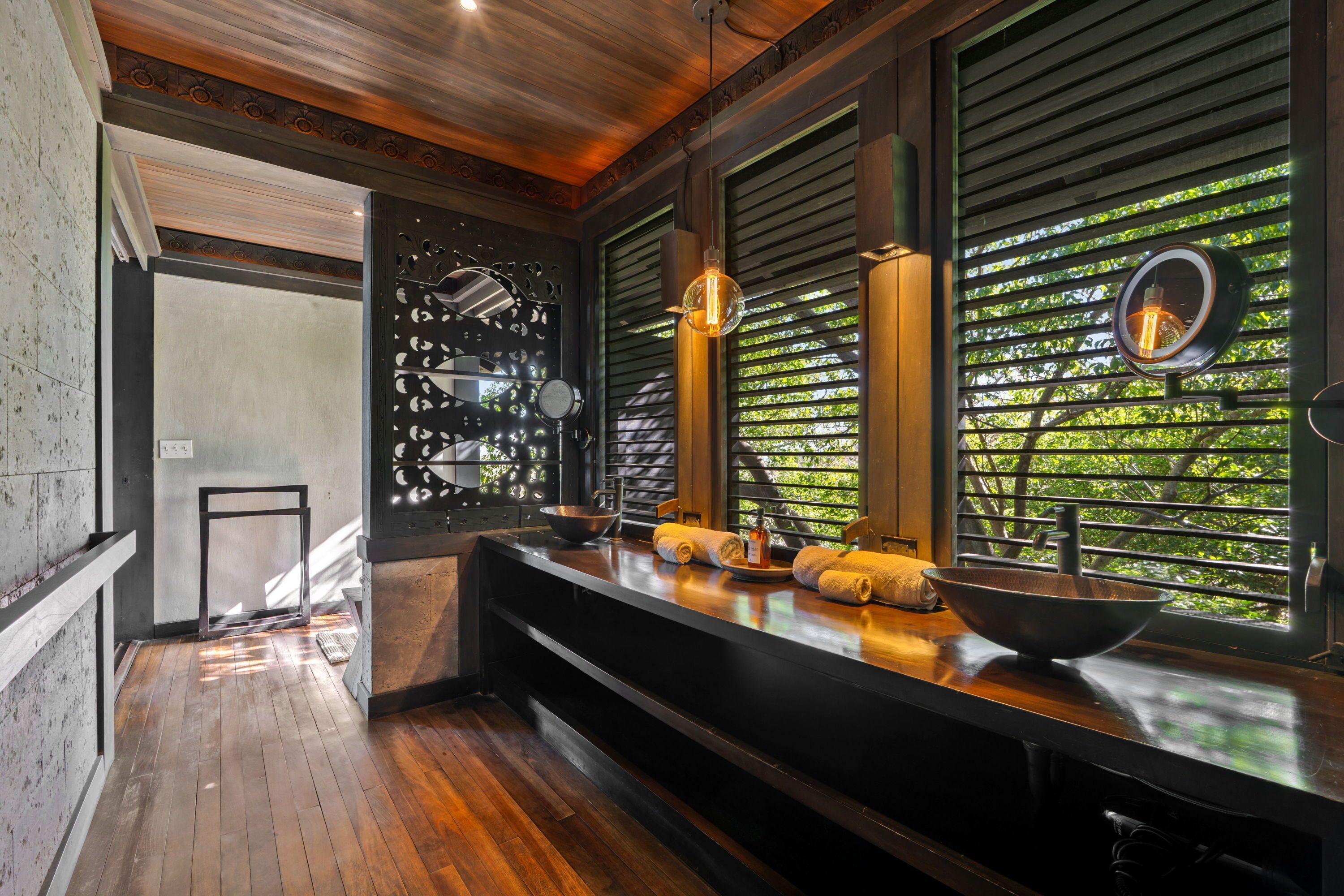 Une salle de bain moderne avec un plancher en bois, un comptoir noir et une fenêtre équipée de stores.