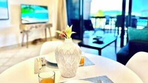 A modern hotel room with a dining area featuring a round table, a vase with flowers, and a glass of orange juice. - Sapphire Beachfront Renovated Villa 1200 SF! - Free Wi-Fi, Generator (St Thomas)
