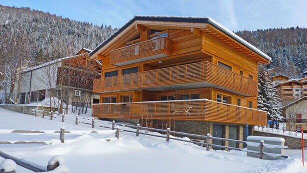 A multi-story wooden chalet with balconies, set in a snowy mountainous area. - Cosy apartment for 4 guests with WIFI, TV and balcony (Ovronnaz)
