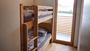 A small room with a wooden bunk bed and a sliding glass door leading to a balcony. - Cosy apartment for 4 guests with WIFI, TV and balcony (Ovronnaz)