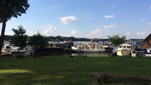 A marina with several boats docked, grassy areas, and trees.