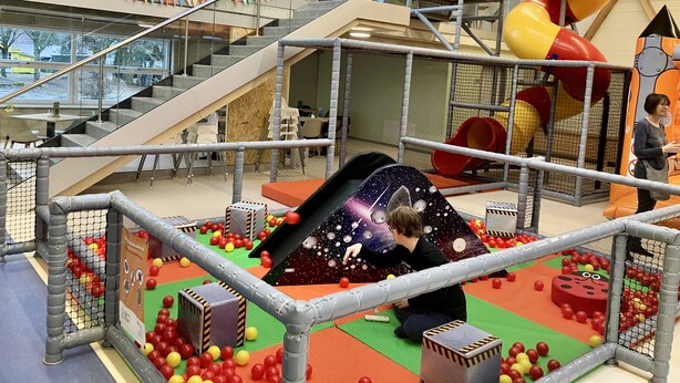 A multi-level indoor play area with a slide, ball pit, and climbing structures.
