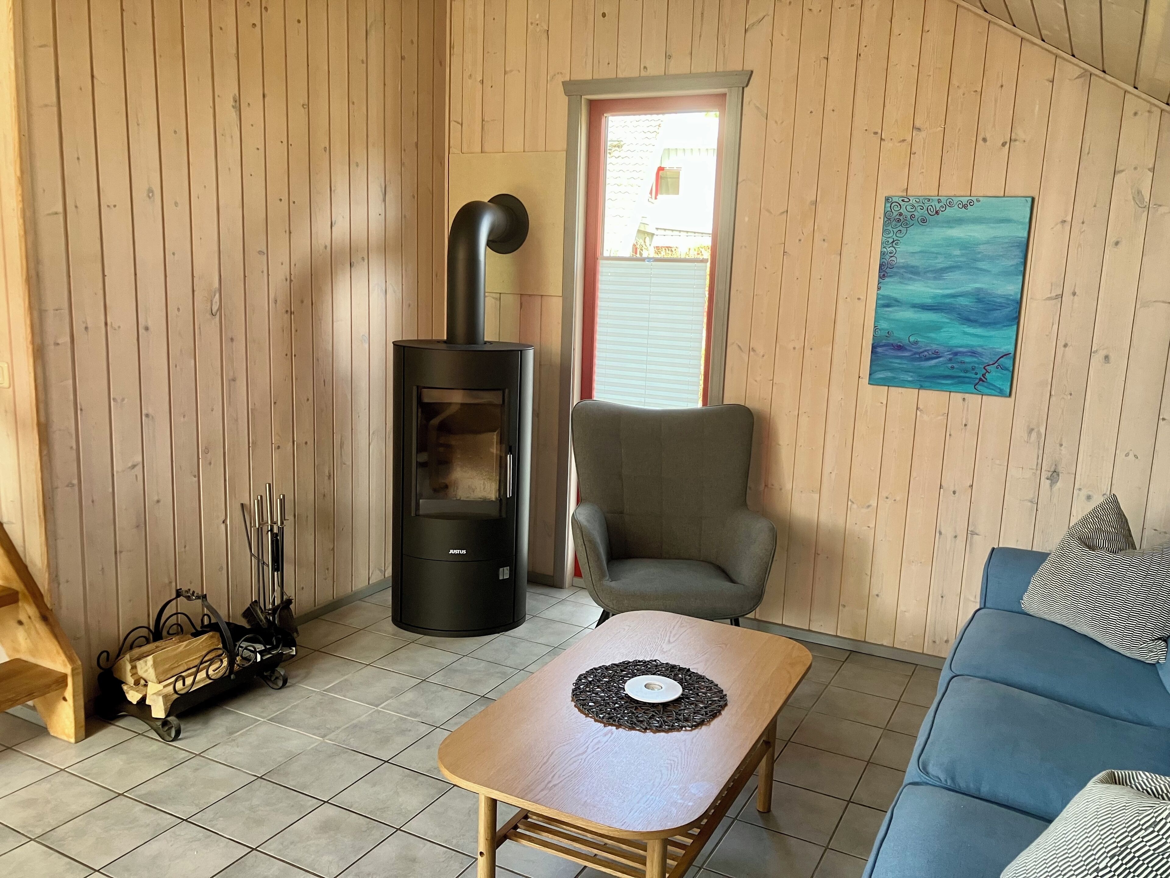 A cozy living room with a modern wood-burning stove, a comfortable sofa, and a dining table.