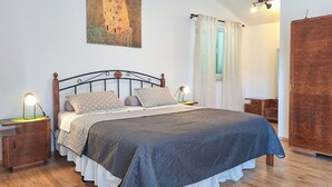 A bedroom with a large bed, wooden headboard, two bedside tables with lamps, a wardrobe, and a painting on the wall. - Wonderful private villa with WIFI, private pool, A/C, TV, terrace, pets allowed and panoramic view (Buzet)