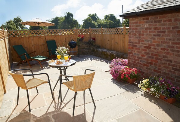 A patio with a table, chairs, a grill, and potted plants.