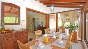 A dining area with a wooden table set for breakfast, a refrigerator, and a view of the outdoors. - Es Pou - Charming villa with pool in Biniamar, Selva, Mallorca (Selva)