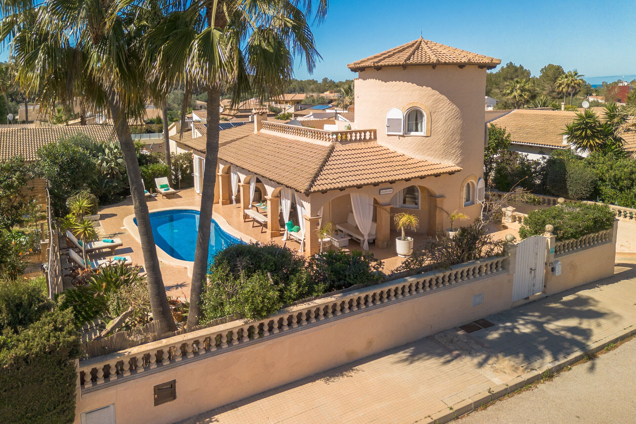 Una villa de estilo mediterráneo con piscina, mobiliario exterior y jardines exuberantes.