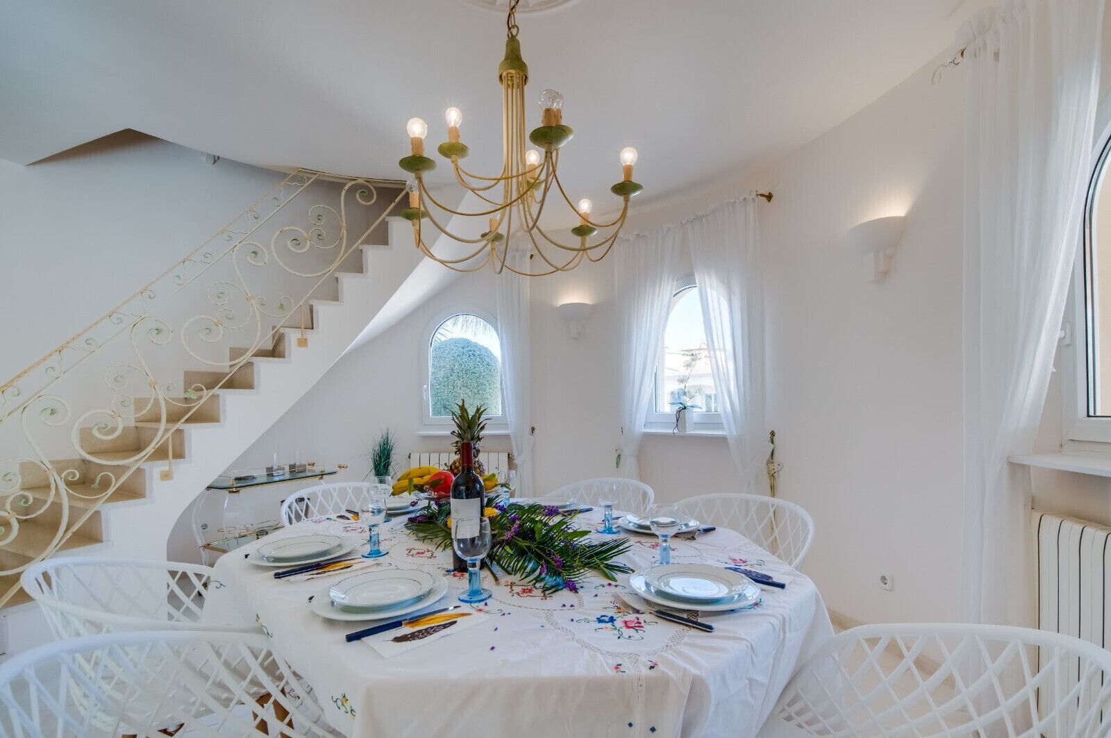 A dining area with a chandelier, white tablecloth, and chairs.