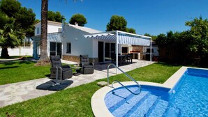 Une maison moderne dotée d’une piscine, d’un espace extérieur aménagé et d’un coin barbecue.