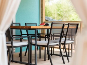 A dining area with a wooden table and black metal chairs with mesh backs.