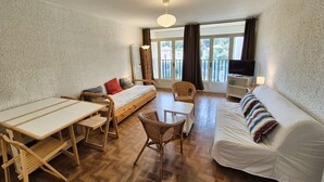 Una habitación pequeña con cama, sofá, mesa de comedor y televisor.