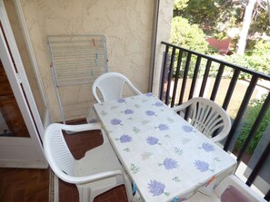 A small balcony with a table and two chairs, a metal drying rack, and a view of greenery. - Big Studio in the peace with SWIMMING POOL and in 5mn in feet of the BEACH (LA SEYNE SUR MER)