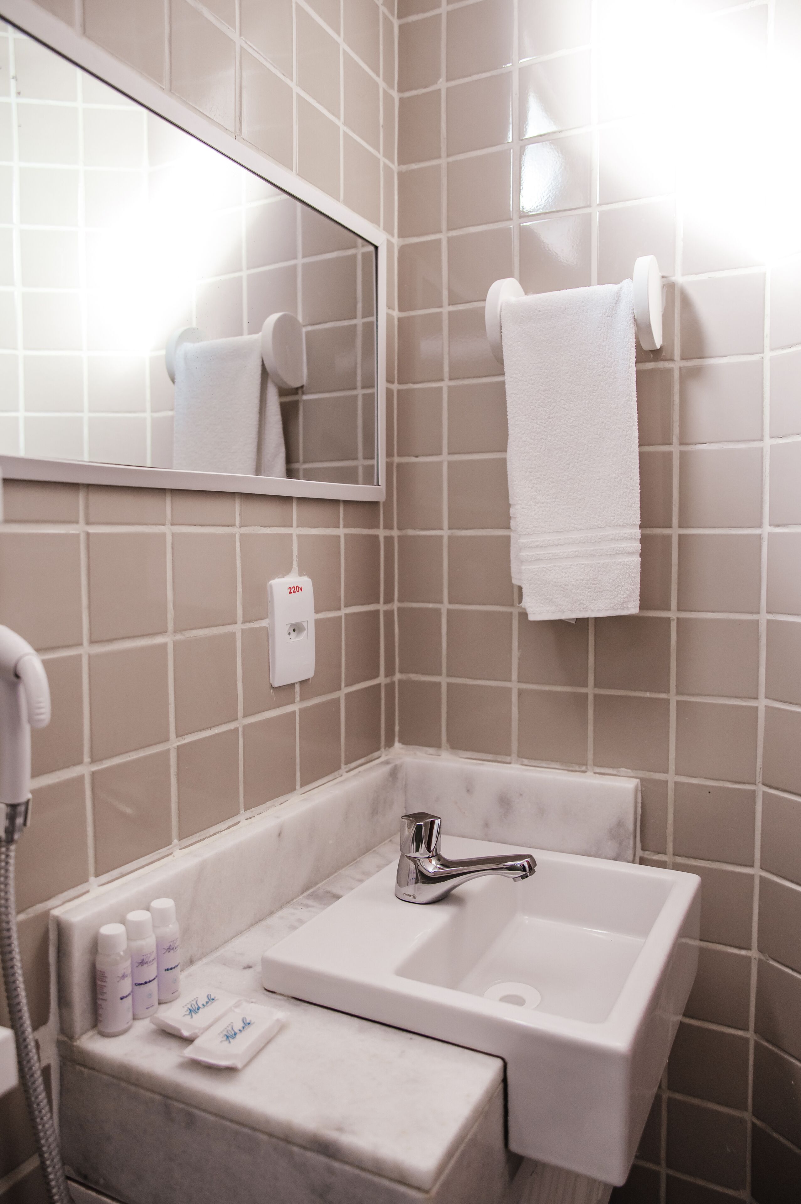 A bathroom with a white sink, a mirror, and a towel hanging on a wall-mounted towel rack.