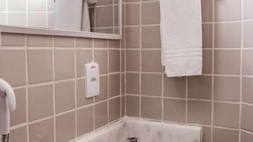 A bathroom with a white sink, a mirror, and a towel hanging on a wall-mounted towel rack.