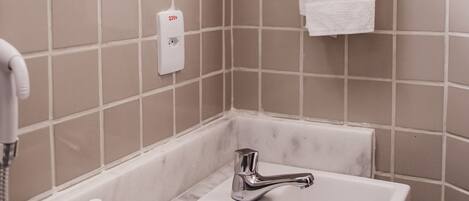 A bathroom with a white sink, a mirror, and a towel hanging on a wall-mounted towel rack.
