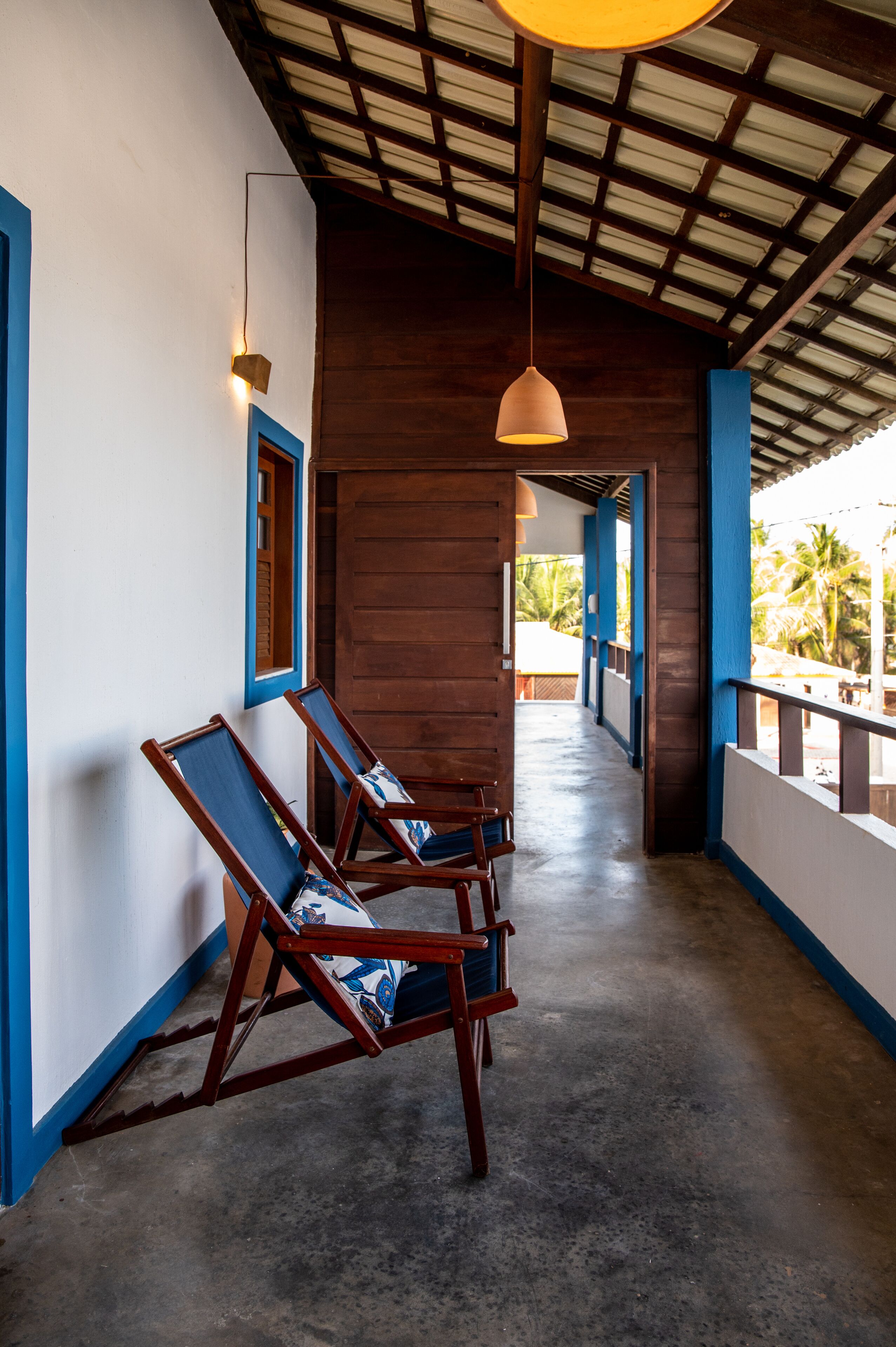 A corridor with wooden chairs and a hanging light fixture.