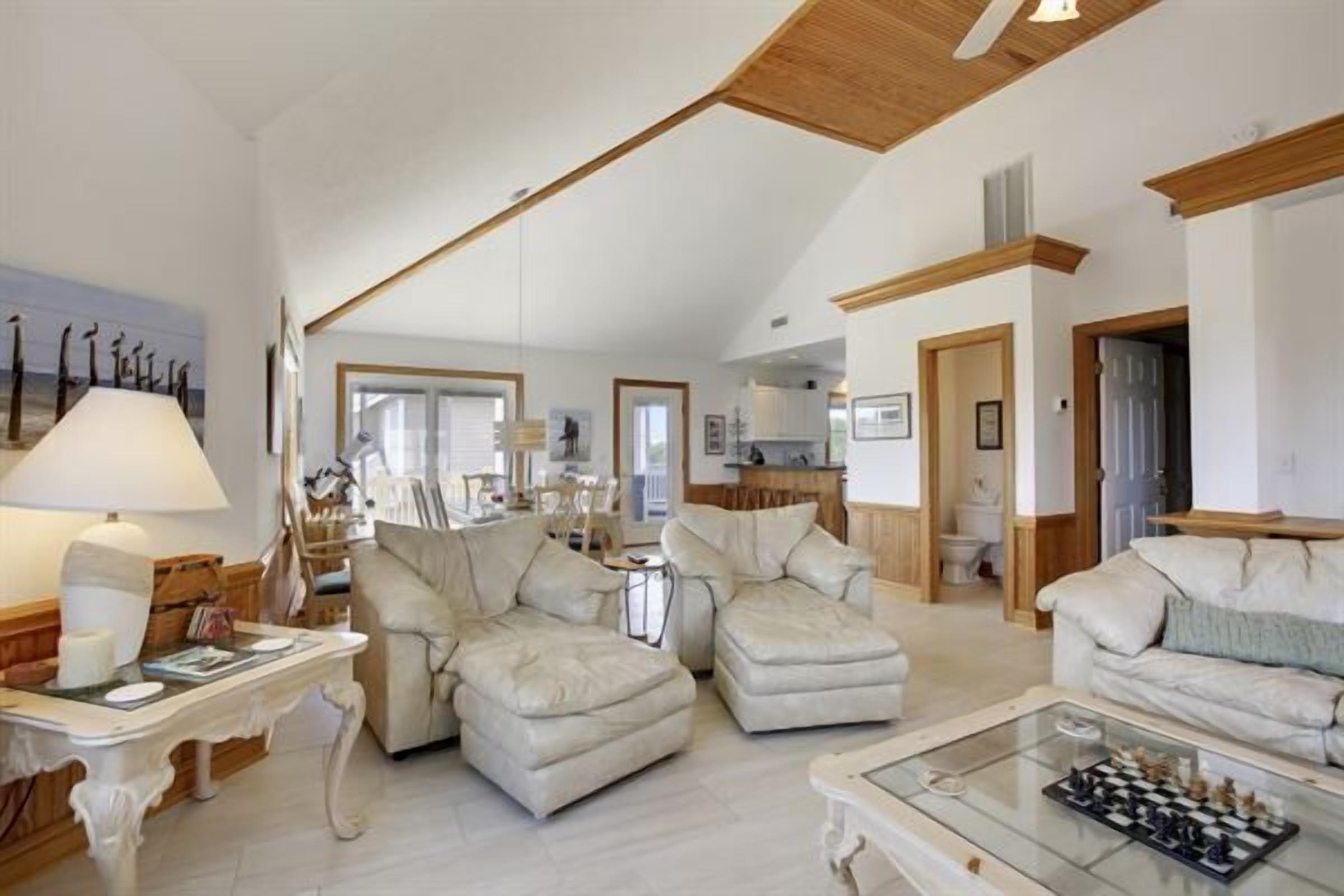 A spacious living room with a high ceiling, a fireplace, and a dining area with a table and chairs.