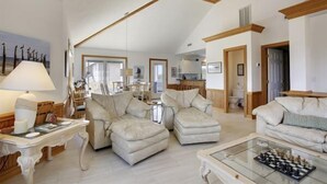 Amplia sala de estar con techo alto, chimenea y comedor con mesa y sillas.