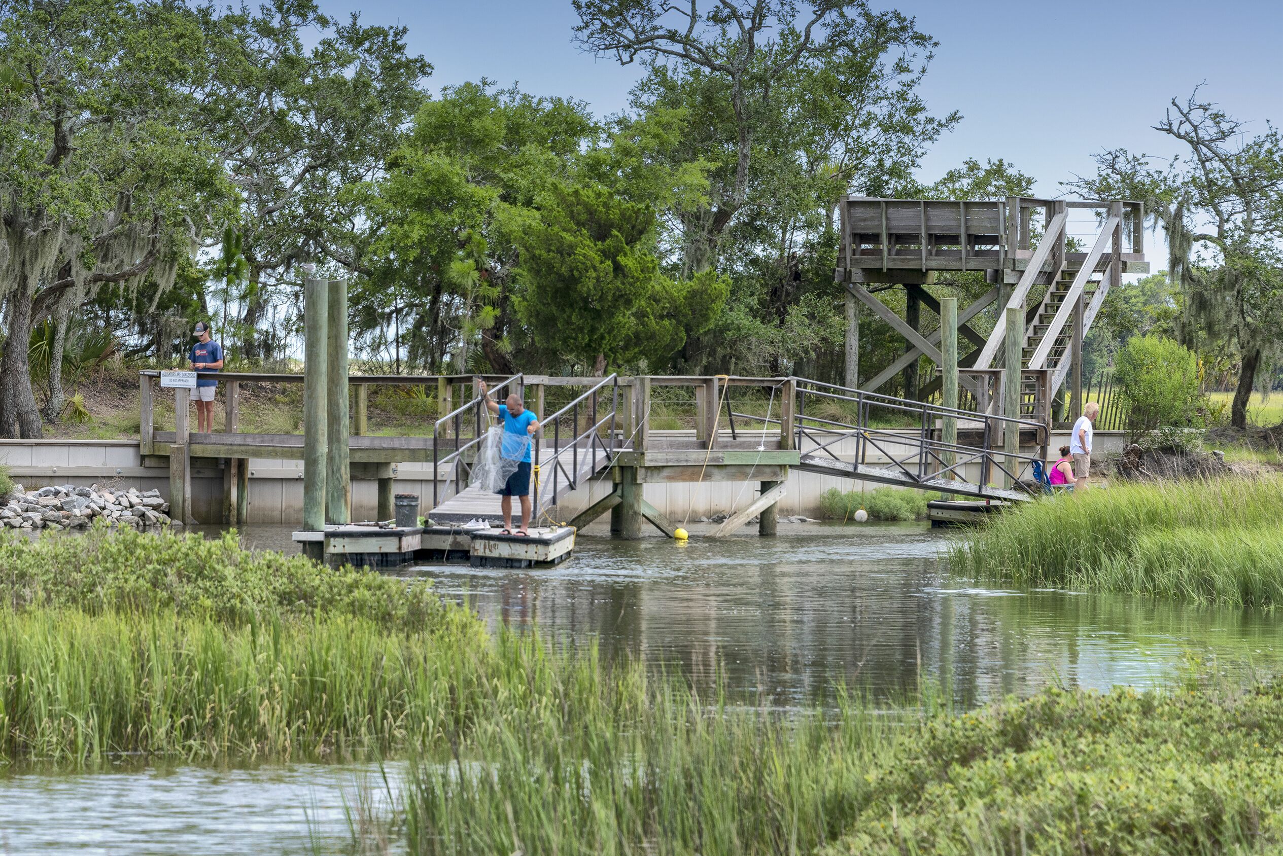 A wooden bridge over a calm river with people walking.