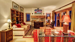 A cozy living room with a fireplace, a sofa, a coffee table, and a bookshelf. - The Crescent Ridge, 2BR Ski Condo, Walk to Lifts! (Park City)