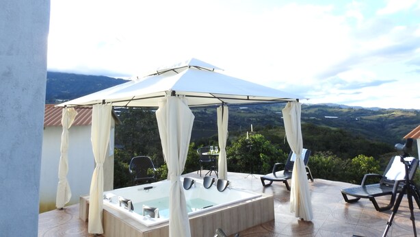 Un espace extérieur abrité, doté d’un jacuzzi et de chaises longues, offrant une vue sur un paysage montagneux.